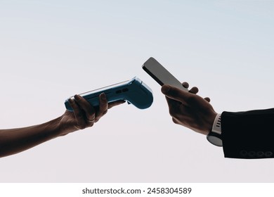 Hands scan bill with card reader for contactless payment on studio background. Customer uses mobile banking app on smartphone to make a convenient cashless payment with mobile wallet NFC technology.  - Powered by Shutterstock