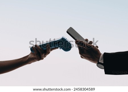Hands scan bill with card reader for contactless payment on studio background. Customer uses mobile banking app on smartphone to make a convenient cashless payment with mobile wallet NFC technology. 
