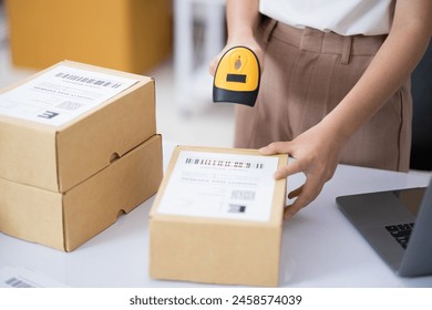 Hands scanning barcode on delivery parcel. Worker scan barcode of cardboard packages before delivery at storage. Woman working in factory warehouse scanning labels on the boxes with barcode scanner. - Powered by Shutterstock