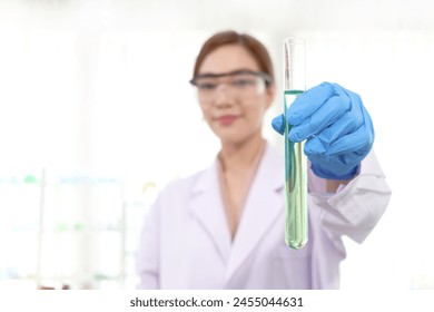 Hands of scientist woman in lab coats with safety glasses holding test tube with green chemical. Researcher uses equipment to do science experiment for research. Female working in science field.

 - Powered by Shutterstock