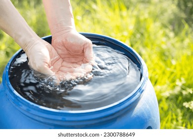 hands scooping water from rainwater tank