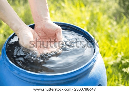 hands scooping water from rainwater tank