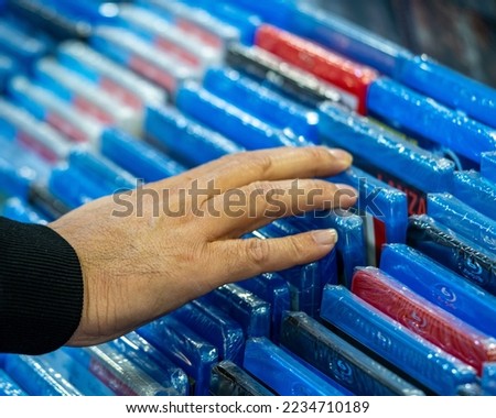 Hands searching and choosing movies and dvds on a shelf in a movie collector's store and merchandising sale of movie discs