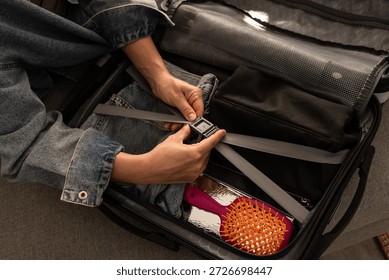 Hands securing compression straps inside packed suitcase.