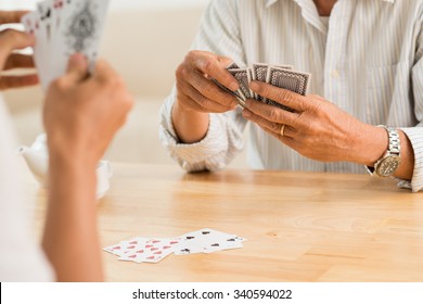 Hands Of Senior Couple Playing Cards At Home