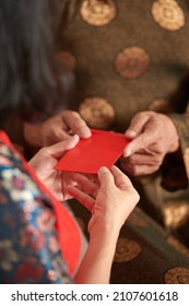 Hands Of Senior Man Giving Red Envelope To His Adult Daughter For Chinese New Year