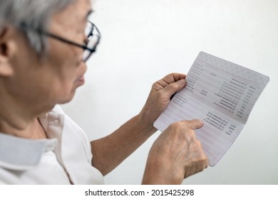 Hands of senior woman holding saving account passbook,checking the sum of money kept and check the amount of elderly pension and subsistence allowance deposits in a bank account,finance in retirement - Shutterstock ID 2015425298