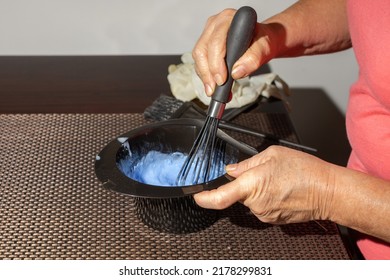 Hands Of A Senior Woman Making A Hair Dye Mixture In A Black Bowl On The Table At Home