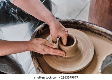 Hands Of Senior Woman Sculpting Clay Vase On Potter's Wheel. Elderly People Concept