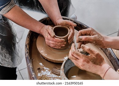 Hands Of Senior Woman Sculpting Clay Vase On Potter's Wheel At Pottery Training Lesson. Hands Of Girl Craftswoman, Teaching Pottery Craft. Hobby Concept