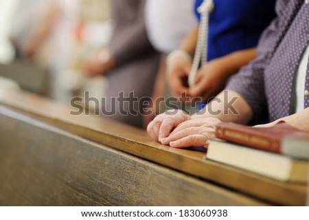 Hands of a senior woman while praying in a church