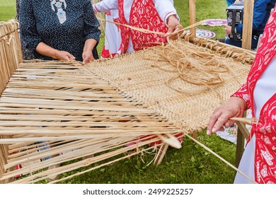 Hands of senior women weave bast cloth on wooden loom at Siberian Tatar festival. Bast weaving is ancient craft. - Powered by Shutterstock