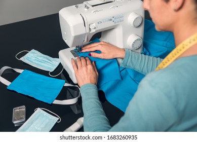 Hands sewing fabric with machine to make homemade surgical masks due to lack of material during covid-19 coronavirus crisis.