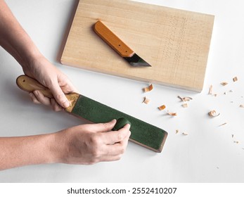 Hands sharpening tool with strop next to cutting board and carving knife - Powered by Shutterstock