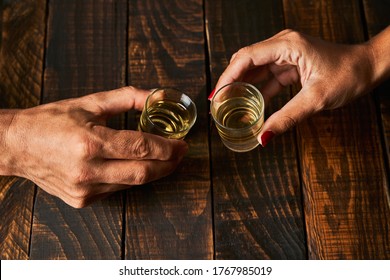 Hands with shot glasses toasting. Concept of alcoholism and addiction.