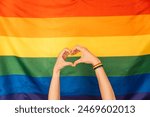 Hands showing heart and love against LGBT flag.