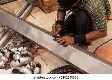 Hands Of Skilled Workers Measure And Mark On Stainless Steel Rain Gutters With The Iron Ingot For Cuts.