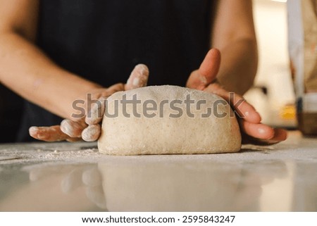 Hands are skillfully rolling and shaping dough on a clean kitchen countertop sprinkled with flour, healthy sourdough bread. The bright space suggests a cozy baking atmosphere.