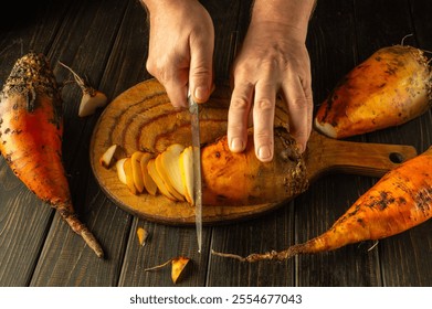 Hands skillfully slice through a vibrant orange beetroot vegetable, surrounded by earthy produce on a rustic wooden cutting board. The warm atmosphere invites culinary creativity. - Powered by Shutterstock