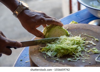 Hands slicing cabbage on the board - Shutterstock ID 1556659742