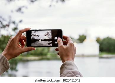 hands with a smartphone in the Park, a girl takes a photo in nature