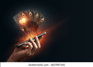 In the hands of a smartphone with playing cards, black-gold background. Concept of online gambling, online casino. Copy space