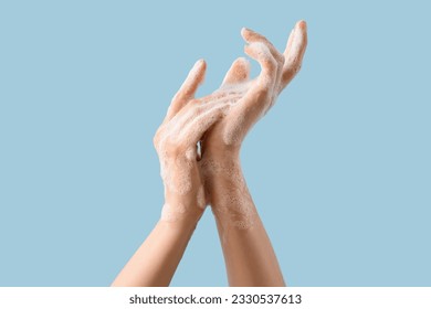 Hands in soap foam on light blue background - Shutterstock ID 2330537613