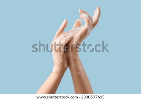 Hands in soap foam on light blue background