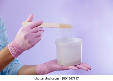 Hands Of A Specialist Of A Beauty Salon Pouring Powder Into Plastic Pot With A Putty Knife