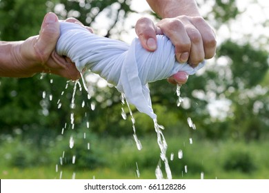 Hands squeeze wet cloth.