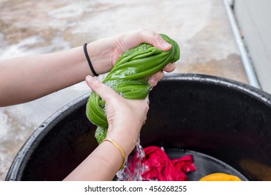 Hands squeeze wet green cloth