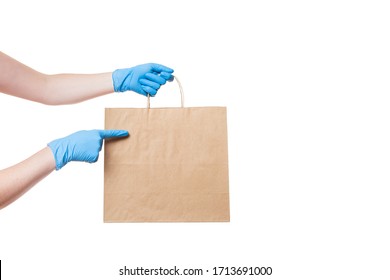 Hands In Sterile Gloves Of A Courier For The Safe Delivery Of Food In An Eco Friendly Craft  Package Points A Finger To An Empty Place For A Logo, Mock Up Isolated On White Background With Copy Space.