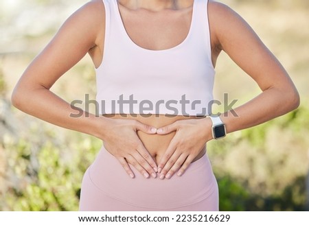 Hands, stomach and fitness of woman with diet, lose weight and wellness goals in park, nature and outdoor healing, training or yoga. Exercise, workout and gut health of girl with digestion hand sign