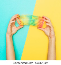 Hands Stretched Rainbow Spiral. Toy From Childhood. Retro Style. Minimalism And Flat Lay
