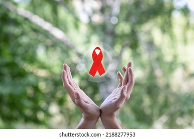 Hands support the symbol of the fight against HIV AIDS and cancer.