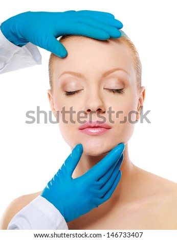 Hands of a surgeon touching the face of a beautiful woman, closeup