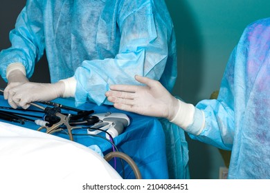 Hands of surgeons in sterile gloves and surgical instruments. Laparoscopic manipulators in the hands of a surgeon. Selective focus. Minimally invasive laparoscopic proctological surgery.
