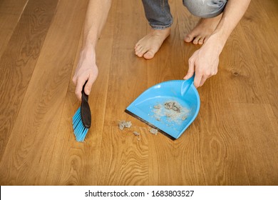 Hands Sweeping Up Dust With Broom And Dust Pan