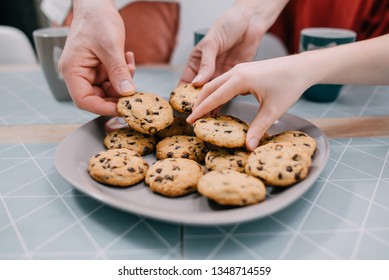Hands take fresh cookies from plate, close-up