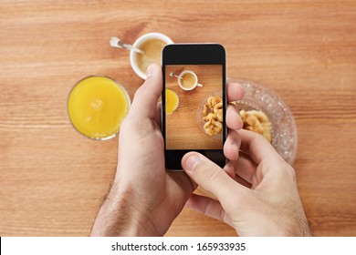 Hands taking photo of breakfast including croissants, cofee and orange juice with smartphone - Powered by Shutterstock