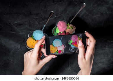 Hands taking photo a Mixed ice cream scoops in glass on a dark background with smartphone - Powered by Shutterstock