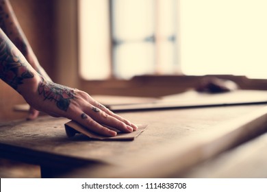 Hands with tattoo using sandpaper on a wood - Shutterstock ID 1114838708