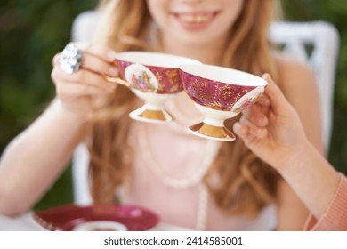 Hands, tea cup and cheers, party and girl children playing with care, celebration and fun in backyard. Closeup of toast, beverage or drink with friends outdoor in garden for game or birthday - Powered by Shutterstock