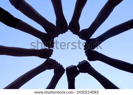 Hands, teamwork and collaboration for community and support with silhouette on sky backdrop. Group of people and fist, together for team, unity and solidarity in workforce with blue background