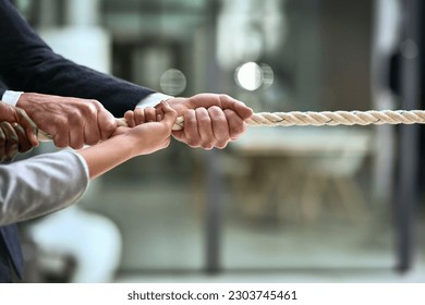 Hands, teamwork and rope with business people pulling during a game of tug of war in the office. Collaboration, help and strength with a team of employees or colleagues holding onto an opportunity - Powered by Shutterstock