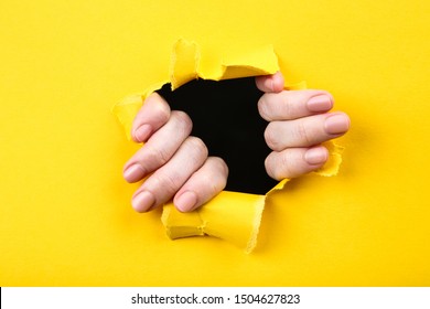 Hands Tearing Hole In Yellow Paper