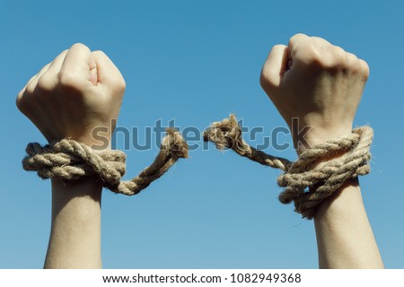 Hands tearing shackles the background of blue sky. Concept of freedom