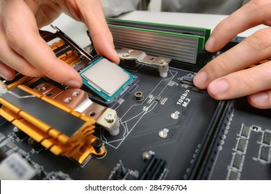 Hands of a technician assembling computer hardware parts, as a new cpu is being mounted unto the motherboard, studio closeup - Shutterstock ID 284796704