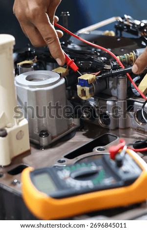 Hands of a technician using a multimeter to check the wiring and solenoid components of an automatic transmission valve body during diagnostic testing and repair.
