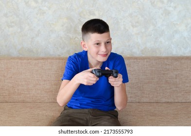 Hands Of A Teenage Child Play A Computer Game Using A Joystick, The Boy Presses The Buttons Of The Remote Control While Playing And Having Fun At Home